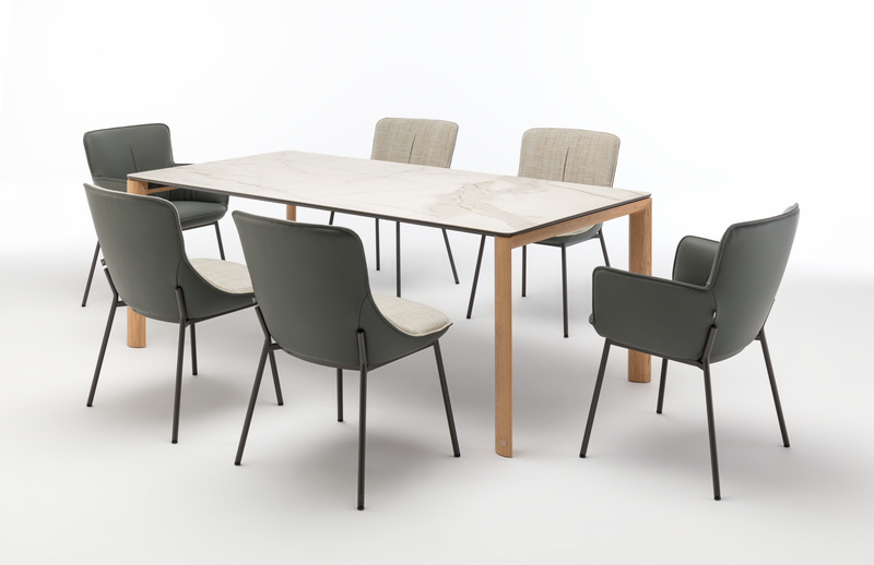 Moderner Esstisch mit Marmorplatte, umgeben von sechs stilvollen Stühlen in grünen und beige Tönen.