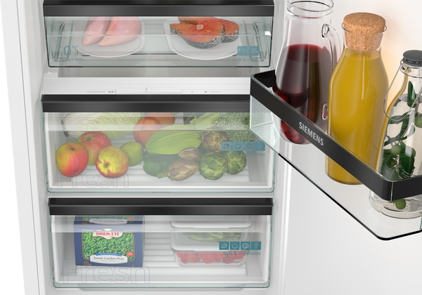 Offener Kühlschrank von Siemens, gefüllt mit frischen Lebensmitteln wie Fleisch, Gemüse und Getränken.