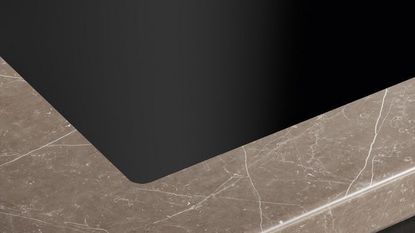 Nahaufnahme einer Marmorarbeitsplatte mit subtilen weißen Adern vor einem dunklen Hintergrund