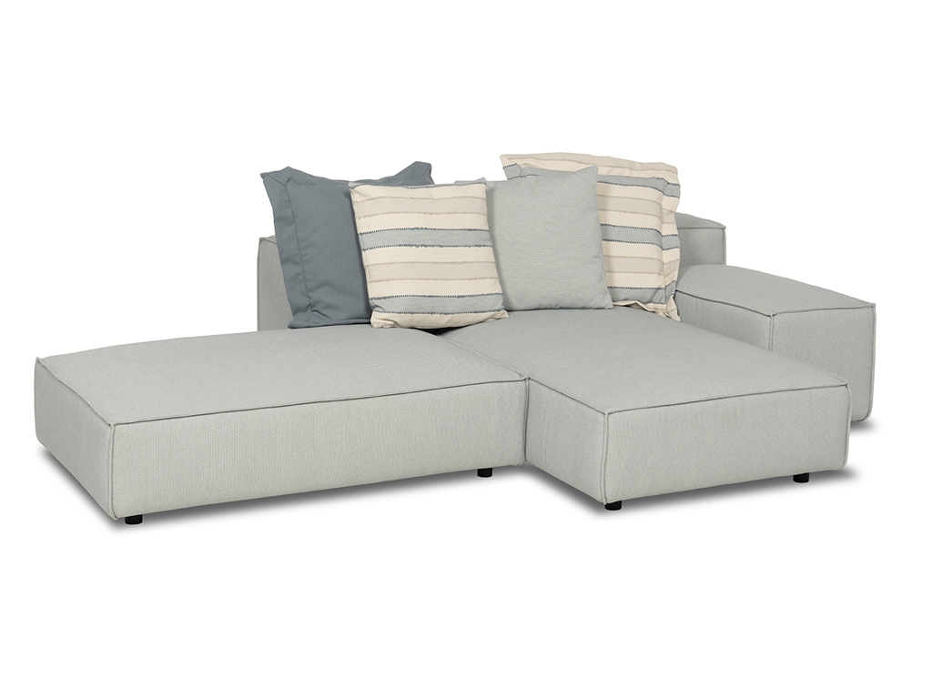 Ein hellgraues, modulares Outdoor-Sofa mit drei verschiedenen Zierkissen in Blau, Hellgrau und gestreift in Blau-Beige. Das Sofa ist aus mehreren Elementen zusammengesetzt und hat eine L-Form. Der Hintergrund ist weiß.