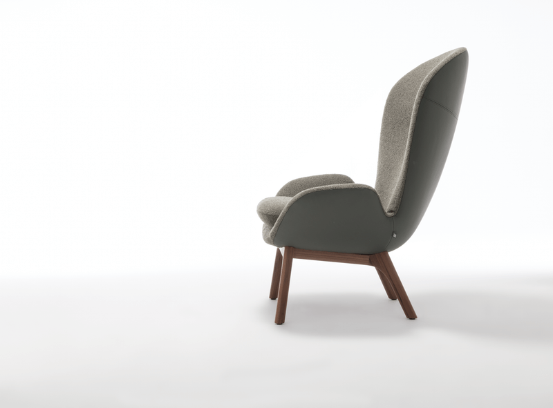 Seitenansicht eines modernen Designer-Sessels mit hoher Rückenlehne und Holzbeinen