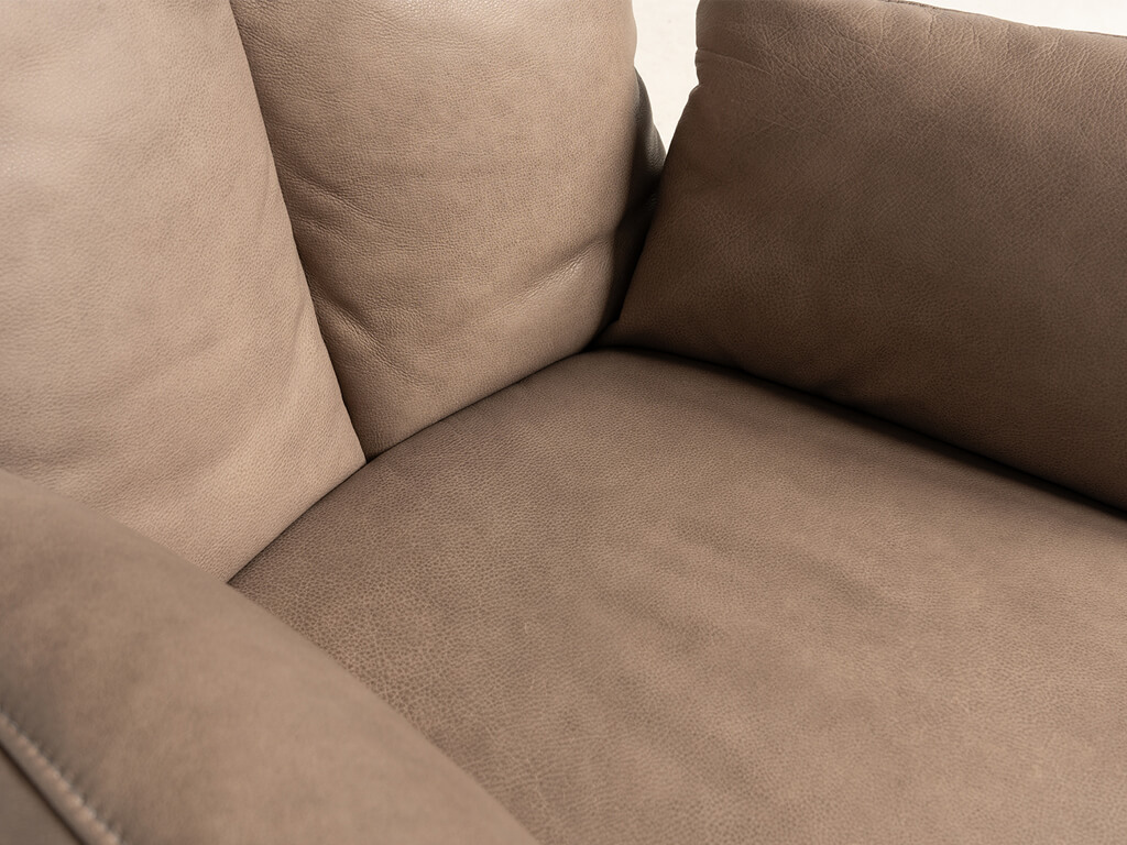 Nahaufnahme der Sitzfläche und Rückenlehne eines beigen Ledersofas mit weicher Polsterung