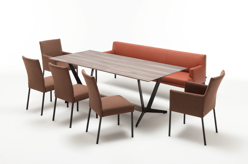 Esszimmermöbel-Set bestehend aus einem langen Esstisch, sechs braunen Stühlen und einem roten Sofa.