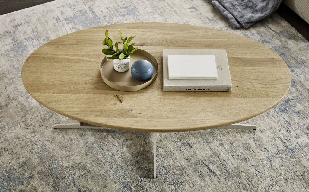 moderner ovaler Holzcouchttisch mit hellem Metallgestellt stilvoll dekoriert in einem modernen Raum auf graue meliertem Teppich