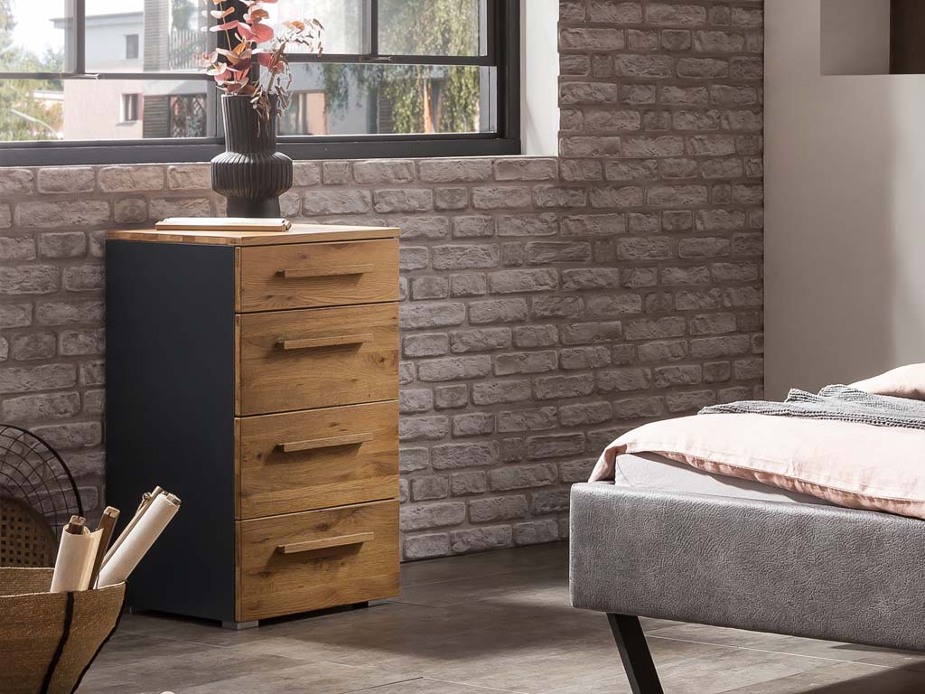 graue kommode mit vier schubladen front und obere seite braun stilvoll dekoriert an einem bett in einem modernen zimmer quatro von hasena