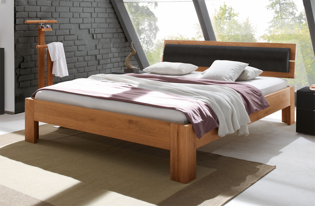 modernes Bett in braun mit Holzkopfteil und Polsterkissen am Kopfteil stilvoll dekoriert in einem modernen Zimmer