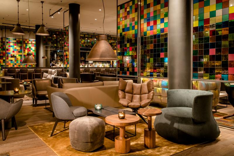 Moderne Lounge mit bequemen Sitzgelegenheiten und bunten Glasfliesen im Hintergrund