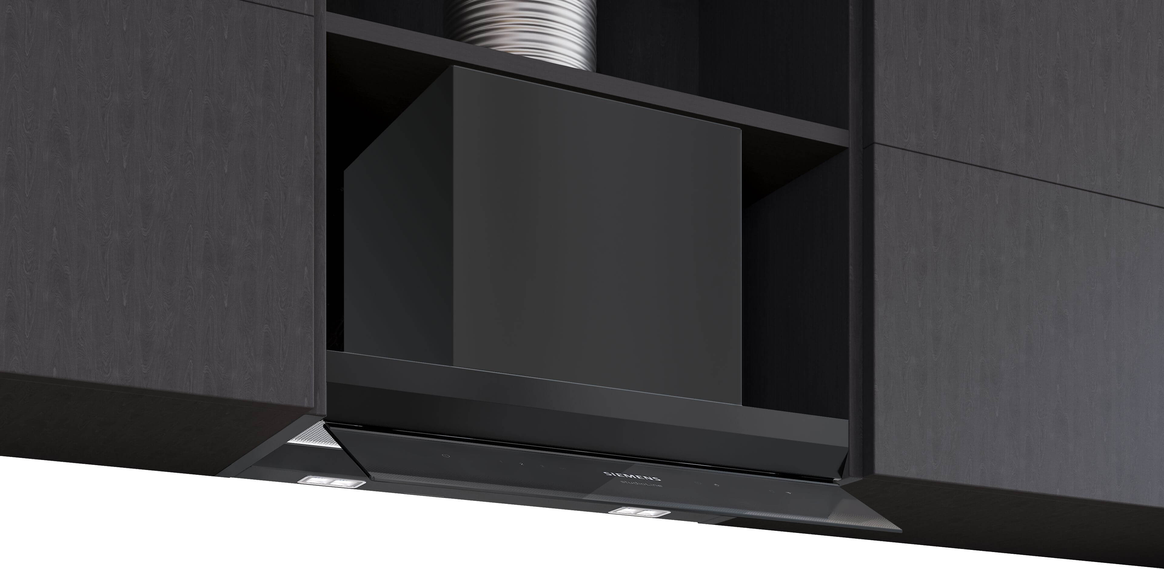 Nahaufnahme der Dunstabzugshaube mit sichtbarem Abluftschlauch: Siemens studioLine Dunstabzugshaube, eingebaut, mit dem metallischen, flexiblen Abluftschlauch sichtbar im Oberschrank.