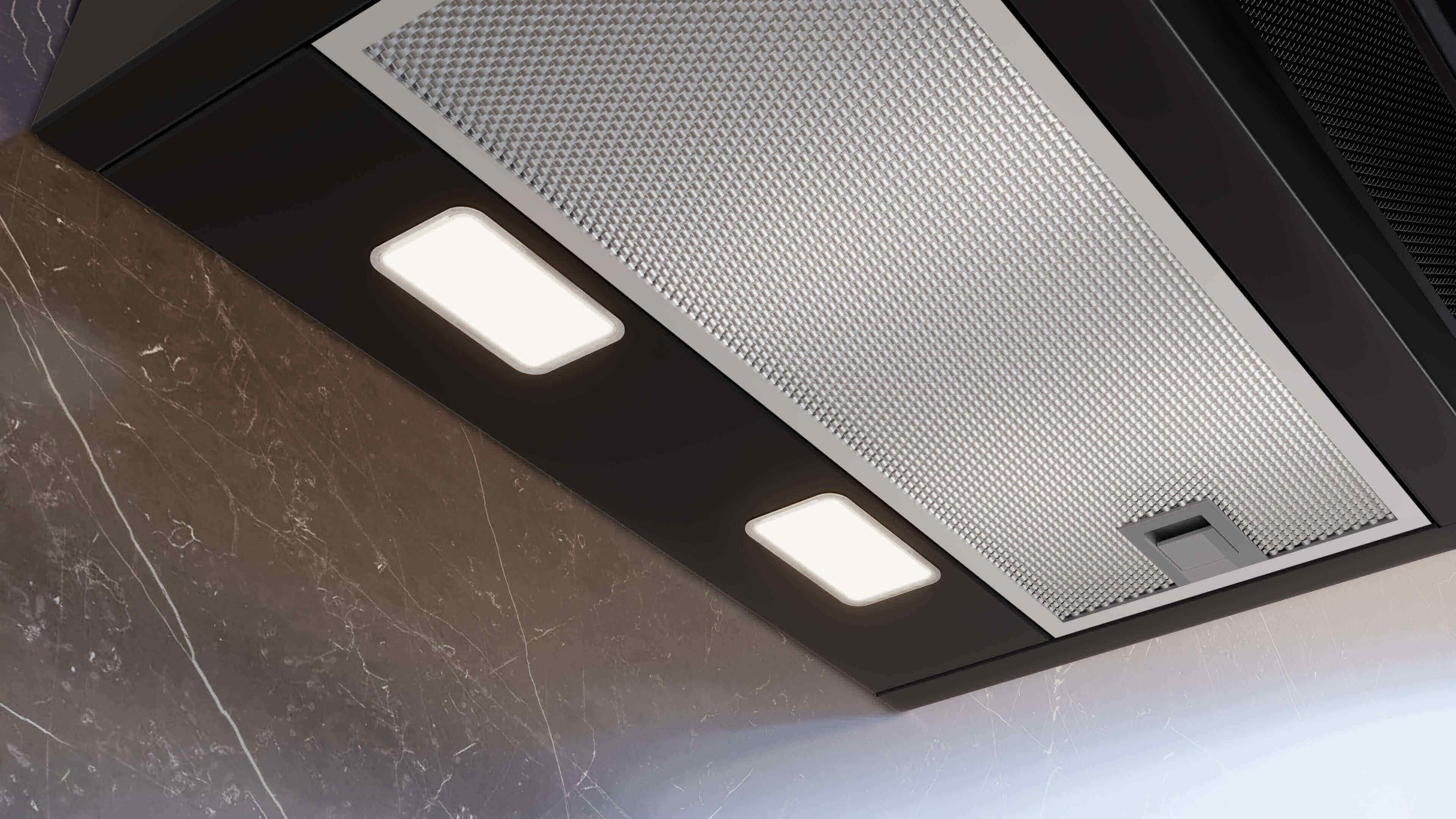 Detailansicht der Unterseite einer schwarzen Dunstabzugshaube mit zwei eingeschalteten, rechteckigen LED-Leuchten und einem feinmaschigen Metallfettfilter.