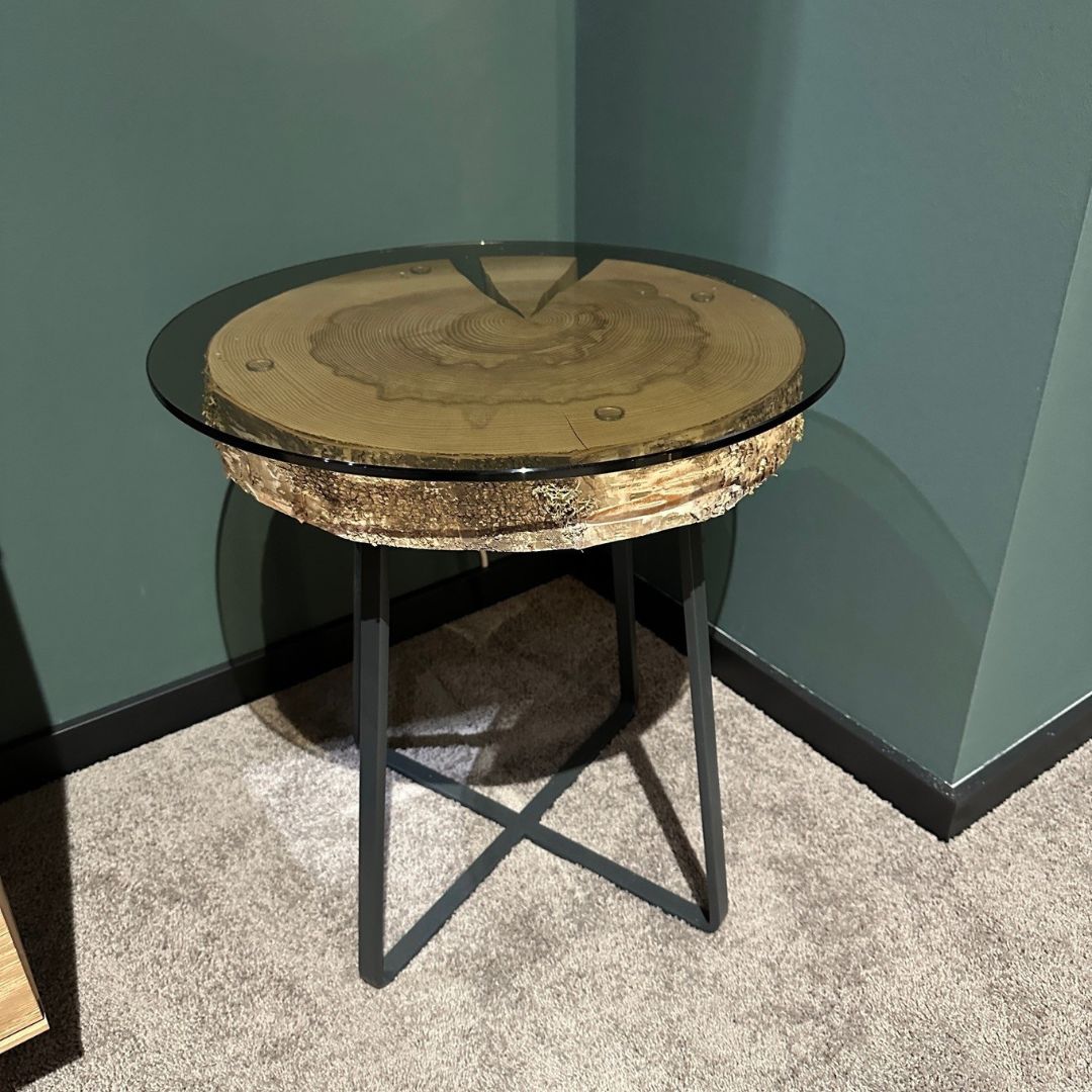 Hartmann NATURSTÜCKE | Beistelltisch Ein runder Beistelltisch mit einer Holzplatte unter einer Glastischplatte auf schwarzem Metallgestell. Perfekt für moderne Wohnzimmer.