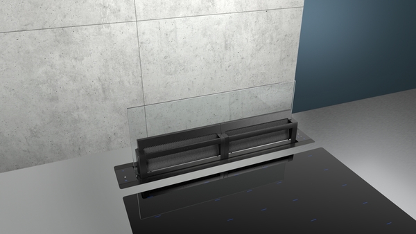 Moderner, versenkbarer Dunstabzug vor grauer Betonwand in einer minimalistischen Küche