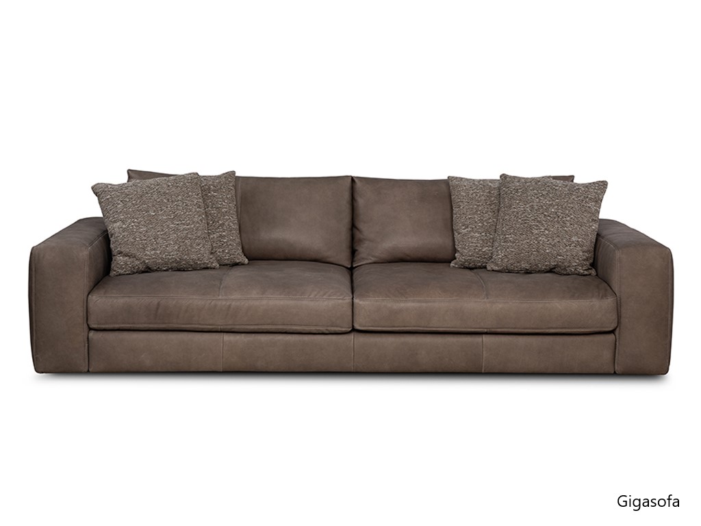 Ein braunes, zweisitziges Ledersofa mit vier beigen, strukturierten Zierkissen. Darunter steht "Gigasofa".