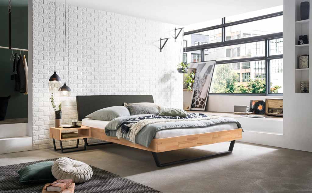Hasena Trento - Bett Sariano | 140 x 200 cm | Kernbuche natur, geölt | Kopfteil Kunstleder grau Gemütliches Schlafzimmer mit modernem Holzrahmenbett, stilvollen Hängeleuchten und großen Fenstern