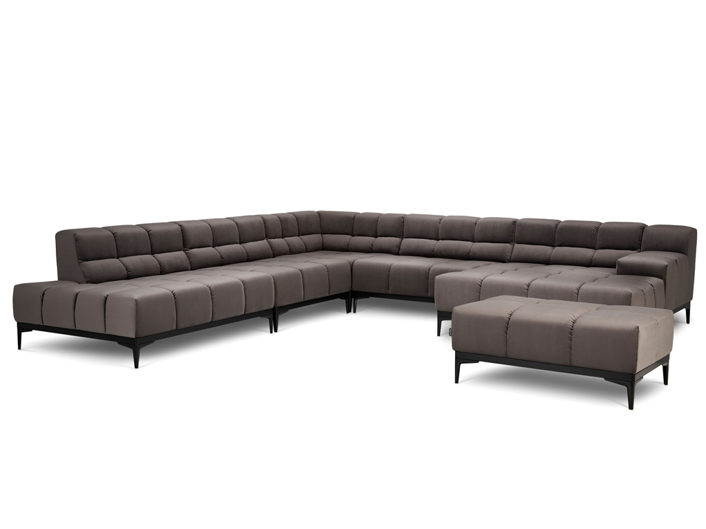 Ein großes U-förmiges Ecksofa in dunklem Taupe mit gesteppten Sitz- und Rückenkissen und schlanken schwarzen Metallfüßen. Es sind keine Zierkissen zu sehen. Ein passender, rechteckiger Hocker steht separat davor. Der Hintergrund ist weiß.