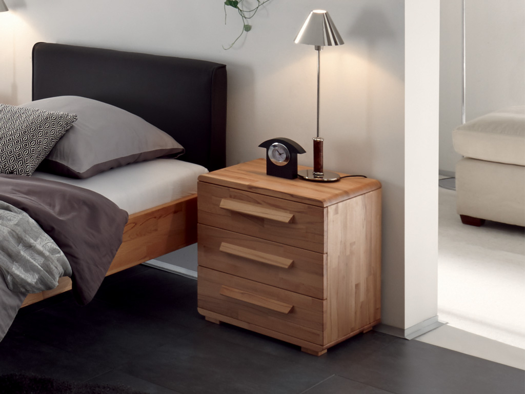 brauner Nachttisch mit drei Schubladen und drei griffen stilvoll dekoriert an einem bett in einem hellen zimmer trigo von hasena