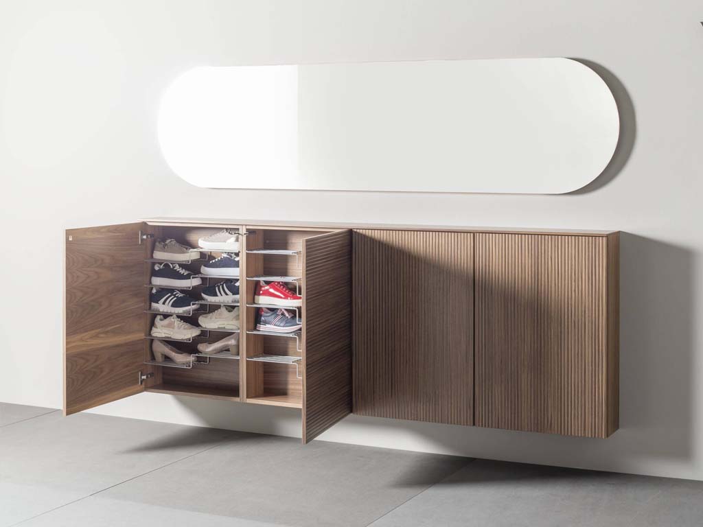 Ein hängender Schuhschrank aus Holz mit offener Tür, der Schuhe in Fächern zeigt, und einem darüberliegenden großen, abgerundeten Spiegel.