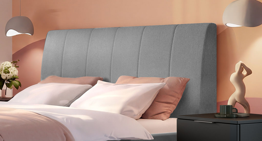 Nahaufnahme des hellgrauen Polsterkopfteils mit vertikaler Steppung und ansprechendem Bettkissen-Arrangement in einem Schlafzimmer (KI-generiert)