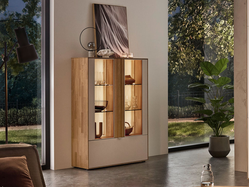 modernes Highboard mit Vitrinenausschnitt und Beleuchtung in braun-weiß stilvoll dekoriert in einem hellen Raum