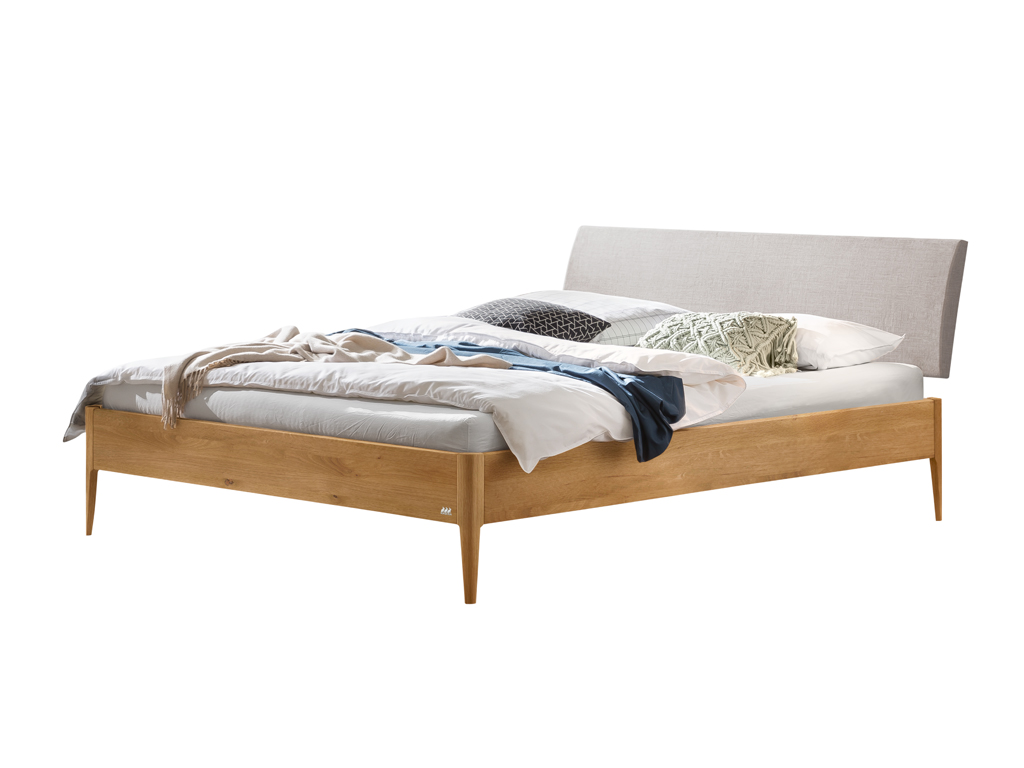Ein fertig montiertes Hasena Fanano Bett mit einem Bettrahmen aus natürlich geölter Wildeiche und einem hellgrauen, gepolsterten Kopfteil. Das Bett ist gemacht mit Bettwäsche und Kissen. Der Hintergrund ist weiß.