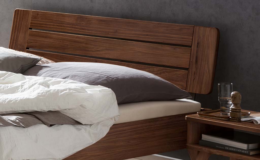 Detailaufnahme eines Holzbettes mit Holzkopfteil und Bettzeug