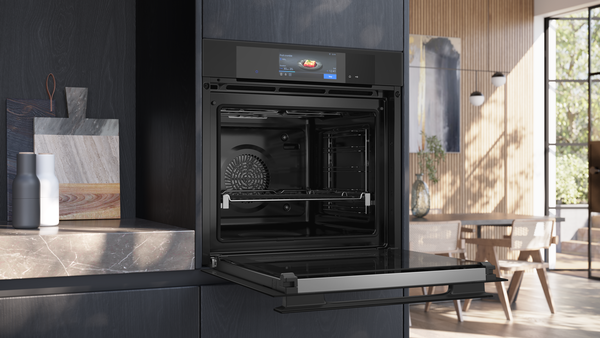 Ein moderner Einbaubackofen in schwarzem Design ist mit vollständig geöffneter Tür in einer stilvollen Küchenumgebung abgebildet.