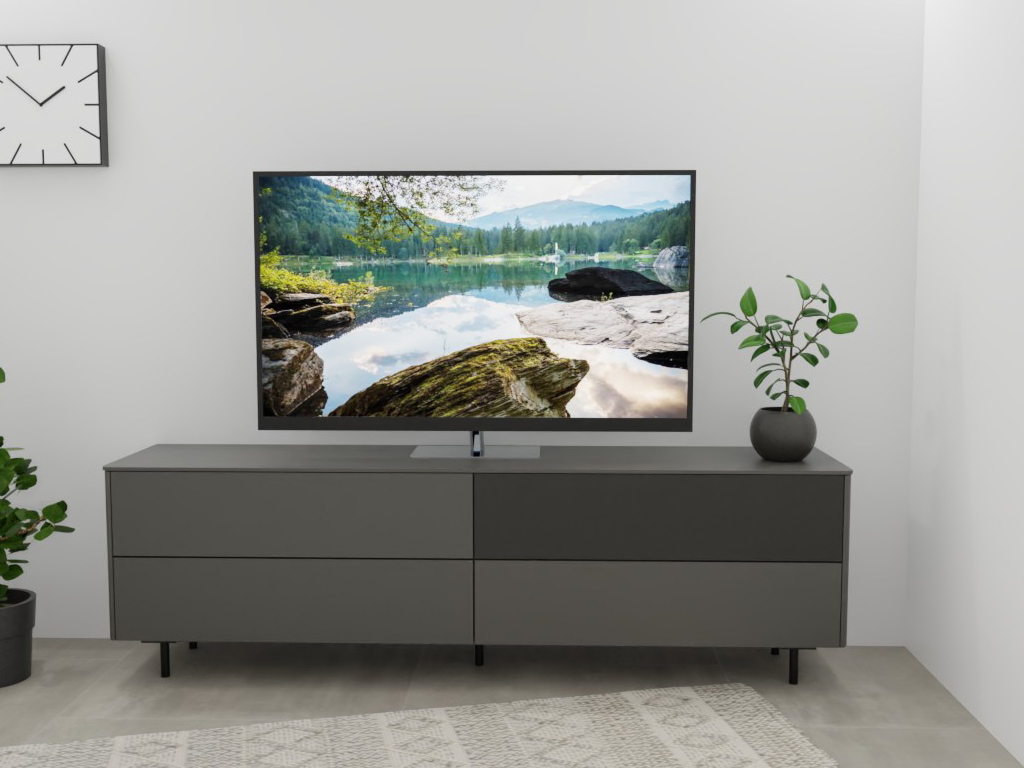 Wohnzimmer mit modernem Fernseher auf grauem Sideboard, daneben eine Zimmerpflanze und eine schlichte Wanduhr
