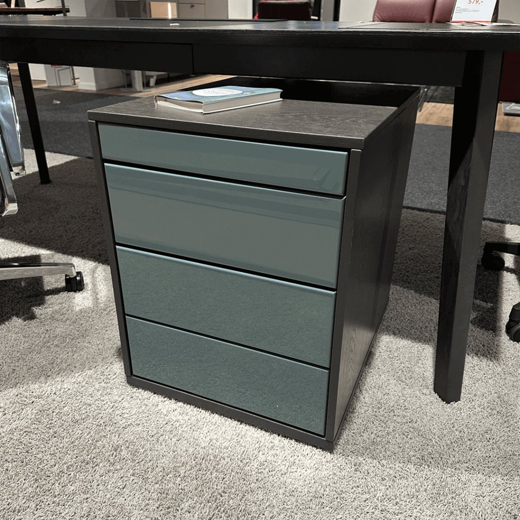 RMW. DEVISO-B | Rollcontainer Kompakter Büroschrank unter dunklem Schreibtisch mit drei Schubladen und Buch darauf