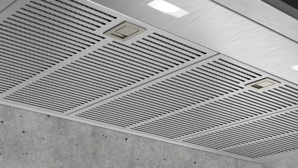 Detailansicht einer modernen Edelstahl-Dunstabzugshaube an einer Betonwand.