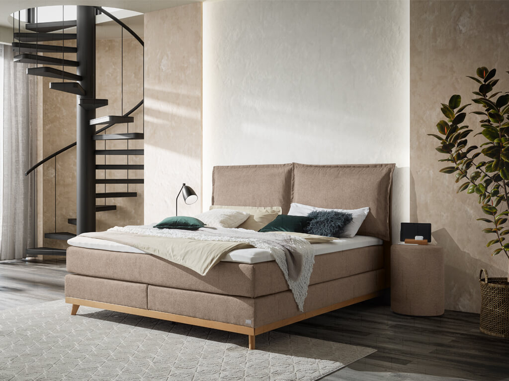 Boxspringbett Hasena Pronto Imelda in Sandfarbe mit einem Holzfußgestell aus geölter Eiche in einem modern eingerichteten Schlafzimmer.