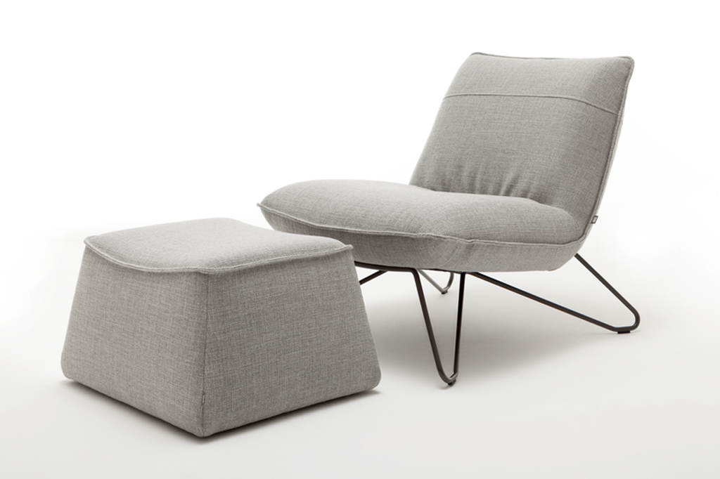 grauer designersessel mit schwarzen metallgestell und polsterhocker vor weißem Hintergrund