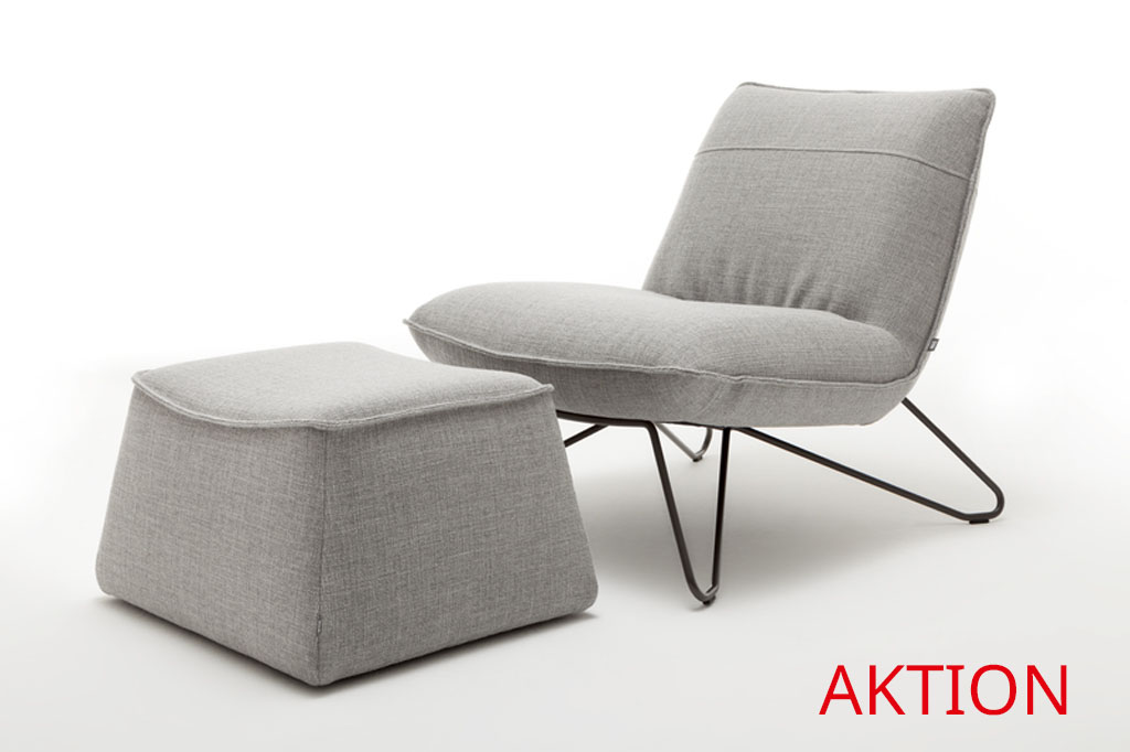 grauer designersessel mit schwarzen metallgestell und polsterhocker vor weißem Hintergrund