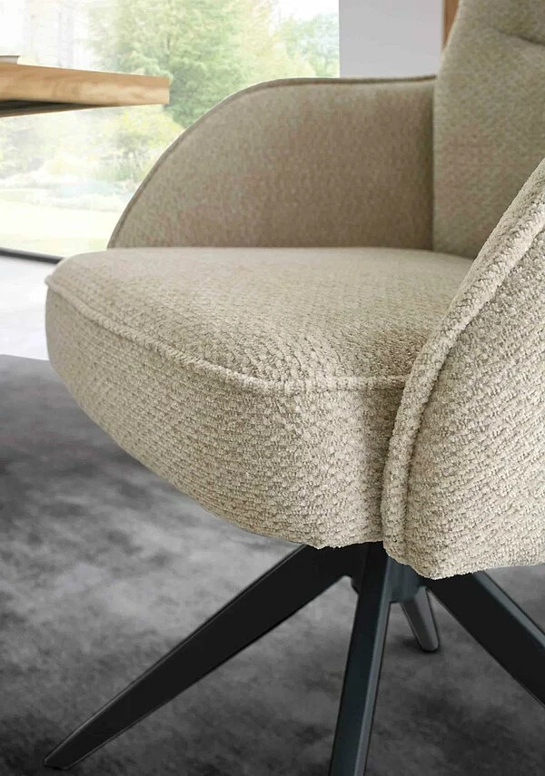 detail eines beigen stuhls mit schwarzem gestell auf grauem teppich