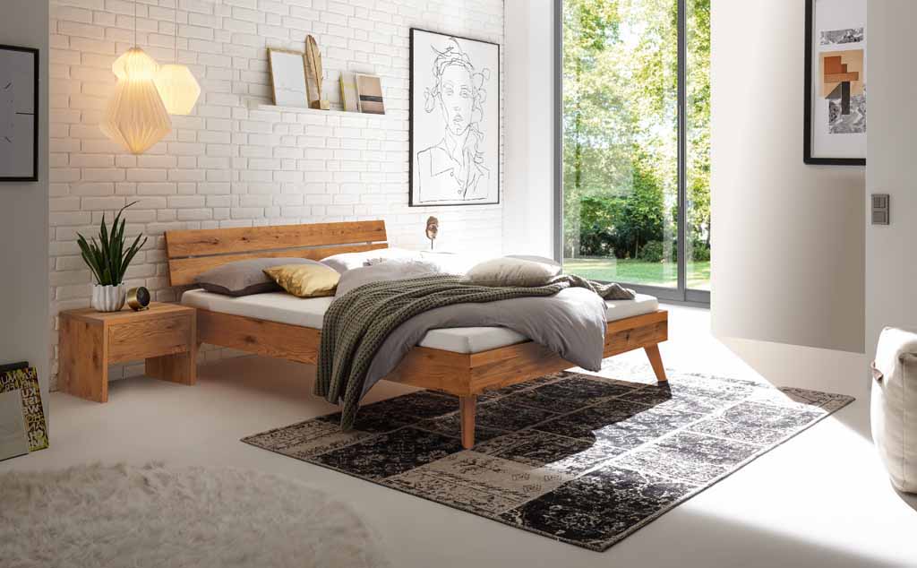 Hasena Trento - Bett Ortona | Wildeiche natur, geölt Stilvoll eingerichtetes Schlafzimmer mit modernem Holz-Doppelbett, Wanddekor und großem Fenster mit Blick ins Freie