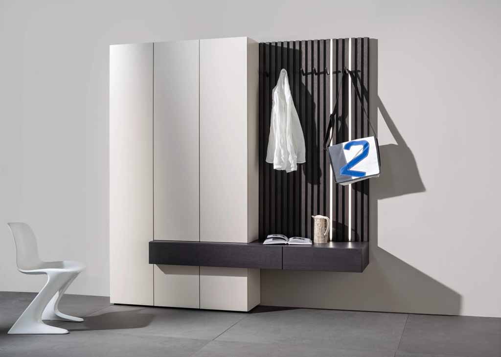 Sudbrock Tando -  Garderobe mit Lamellenpaneele | B: 210,0 cm | Lack blütenweiß, Eiche anthrazit Eleganter Garderobenschrank in Weiß und Dunkelgrau mit Hakenleiste für Kleidung und Taschen, ergänzt durch einen stilvollen Sitzbereich