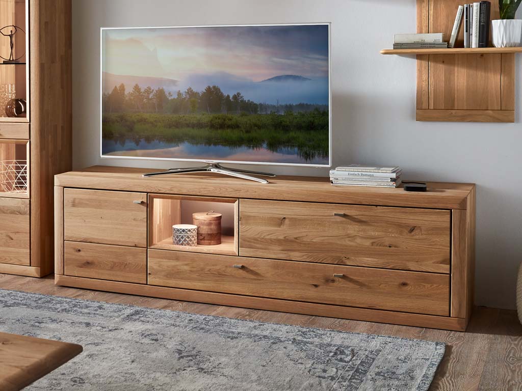Wöstmann Aurum - Lowboard | Type 1053/1054 | Wildeiche massiv | B: 204,2 cm | konfigurierbar Rustikales TV-Lowboard aus Massivholz mit Beleuchtung, dekoriert mit Fernseher und Büchern