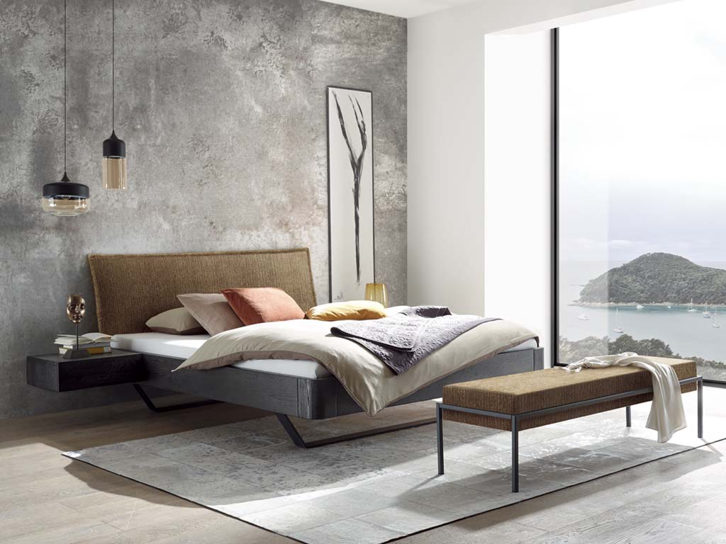 stilvoll dekoriertes Bett mit Bettbank in einem hellen modernen Zimmer vor einer großen Fensterfront