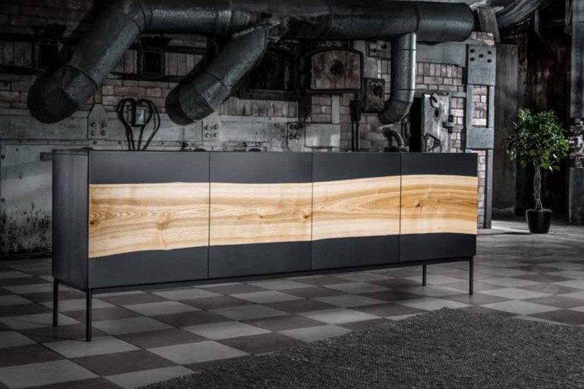 Wimmer 18Hundert | Sideboard | B: 221,5 cm | 152110 Ein stilvolles, dunkles Sideboard mit einer dekorativen Holzverkleidung, platziert in einem Raum mit industriellem Design.
