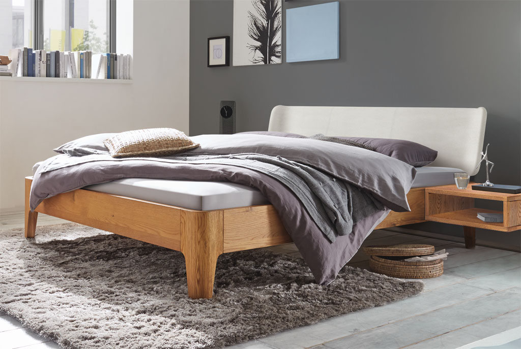 modernes Bett in braun mit geschwungenem Polsterkopfteil in weiß stilvoll dekoriert in einem modernen Zimmer