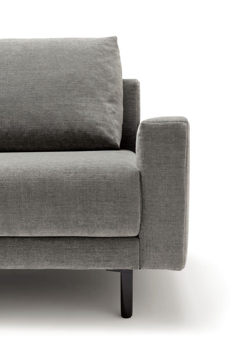 Nahaufnahme eines modernen grauen Sofas mit Armlehne und Kissen