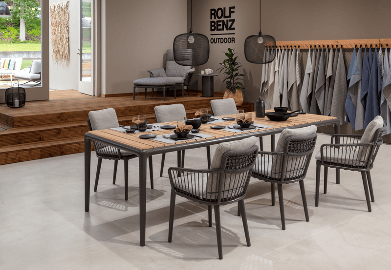 Ein stilvoll eingerichteter moderner Essbereich mit einem großen Esstisch und sechs Stühlen, dekoriert mit Geschirr und Besteck.