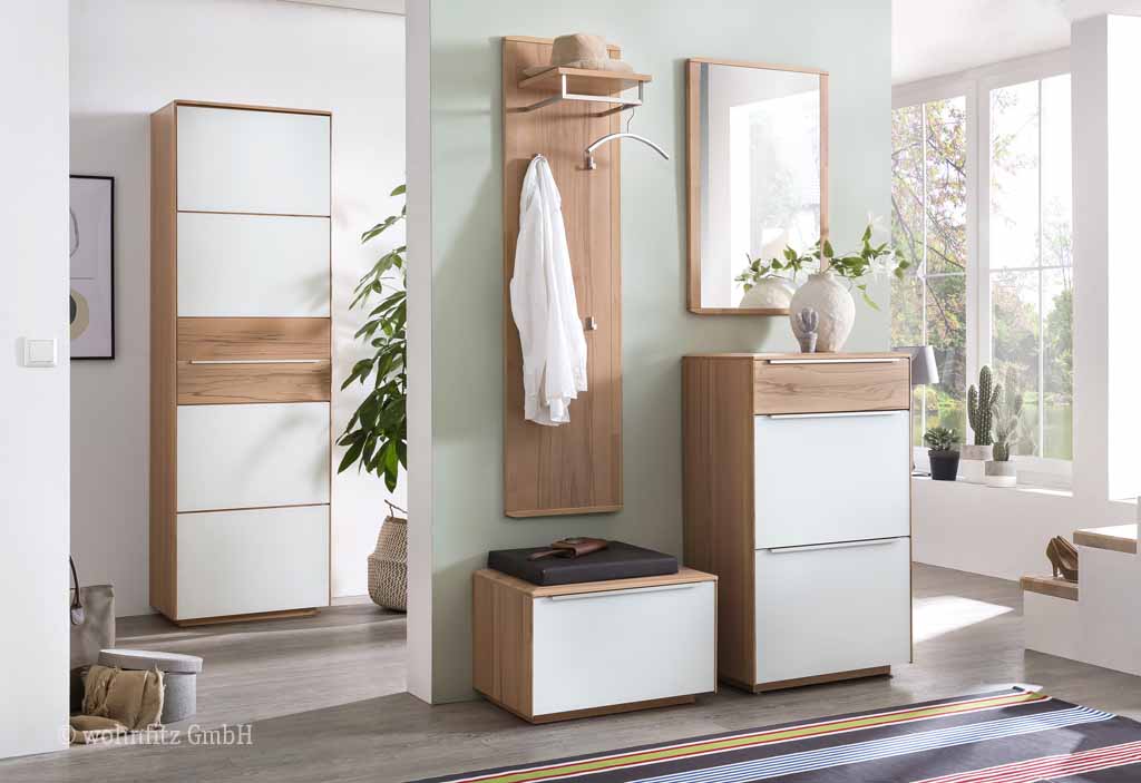 Bienenmühle Novum - Garderoben-Set, 5-teilig | Vorschlag 1 | Kernbuche furniert Wohnbereich mit moderner Garderobe aus Holz und weißen Elementen, bestehend aus einem Schuhschrank, Spiegel und einer Sitzbank, dekoriert mit Pflanzen in einem hellen Raum.