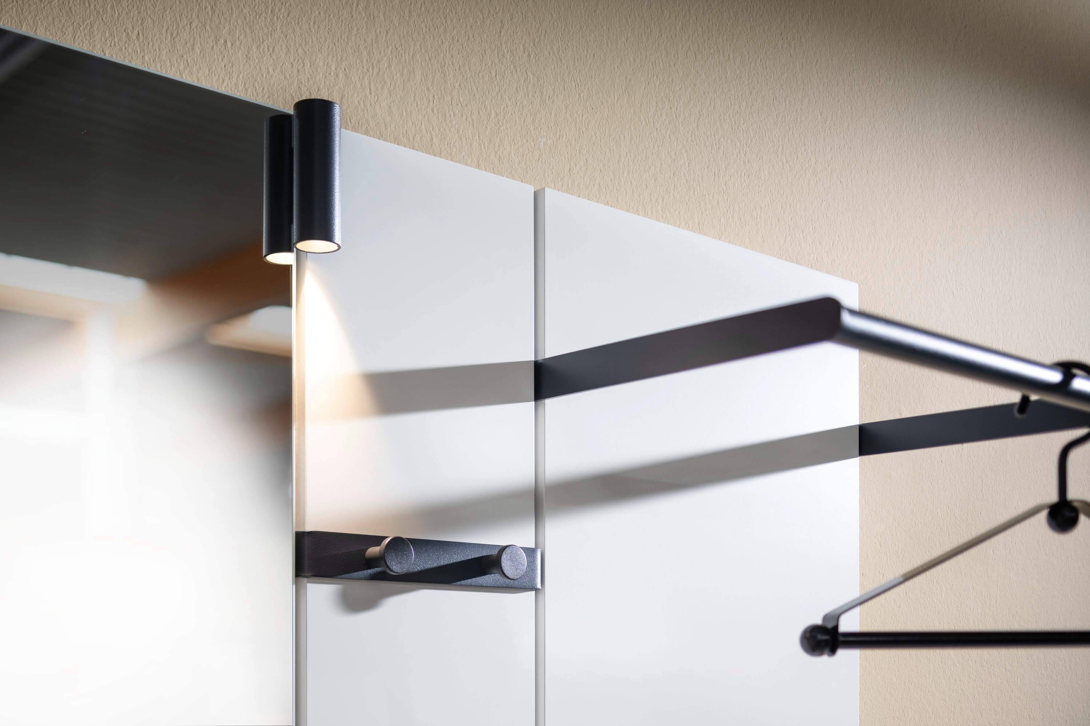 Detailansicht eines modernen Garderobenhakens aus Metall mit integrierter LED-Leuchte an einer Wand.