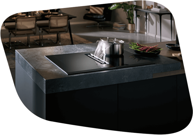 Elegante Kücheninsel mit integriertem Induktionskochfeld, einem Edelstahltopf und Dekorationen in einem stilvollen Raum