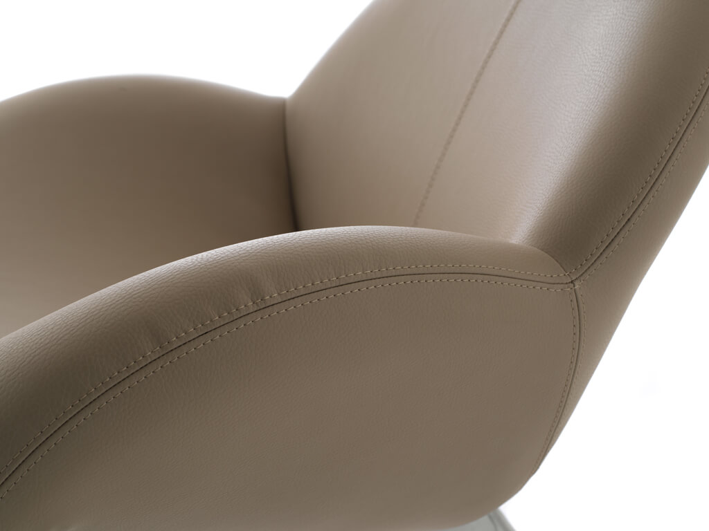 Nahaufnahme eines beigen Ledersessels mit geschwungenen Armlehnen