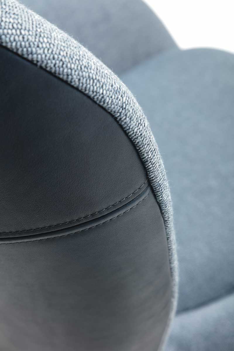 Detailansicht eines Stuhls mit gepolstertem Stoffbezug und Lederakzenten