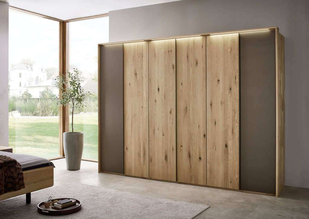 moderner Holzkleiderschrank mit beiden Außentüren in mattem braun und Beleuchtung im Passepartout in einem hellen modernen Raum