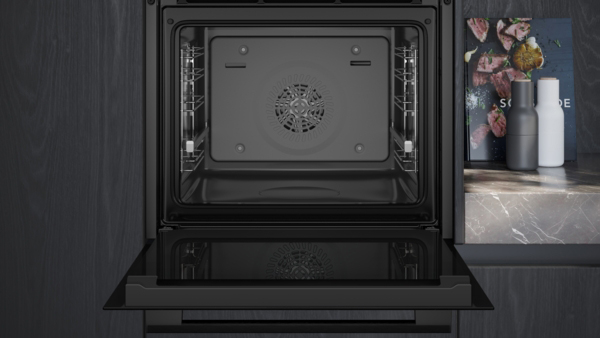 Ein geöffneter Backofen mit einem modernen Design in einer eleganten Küche mit dunklen Schränken und einem Marmorarbeitsbereich