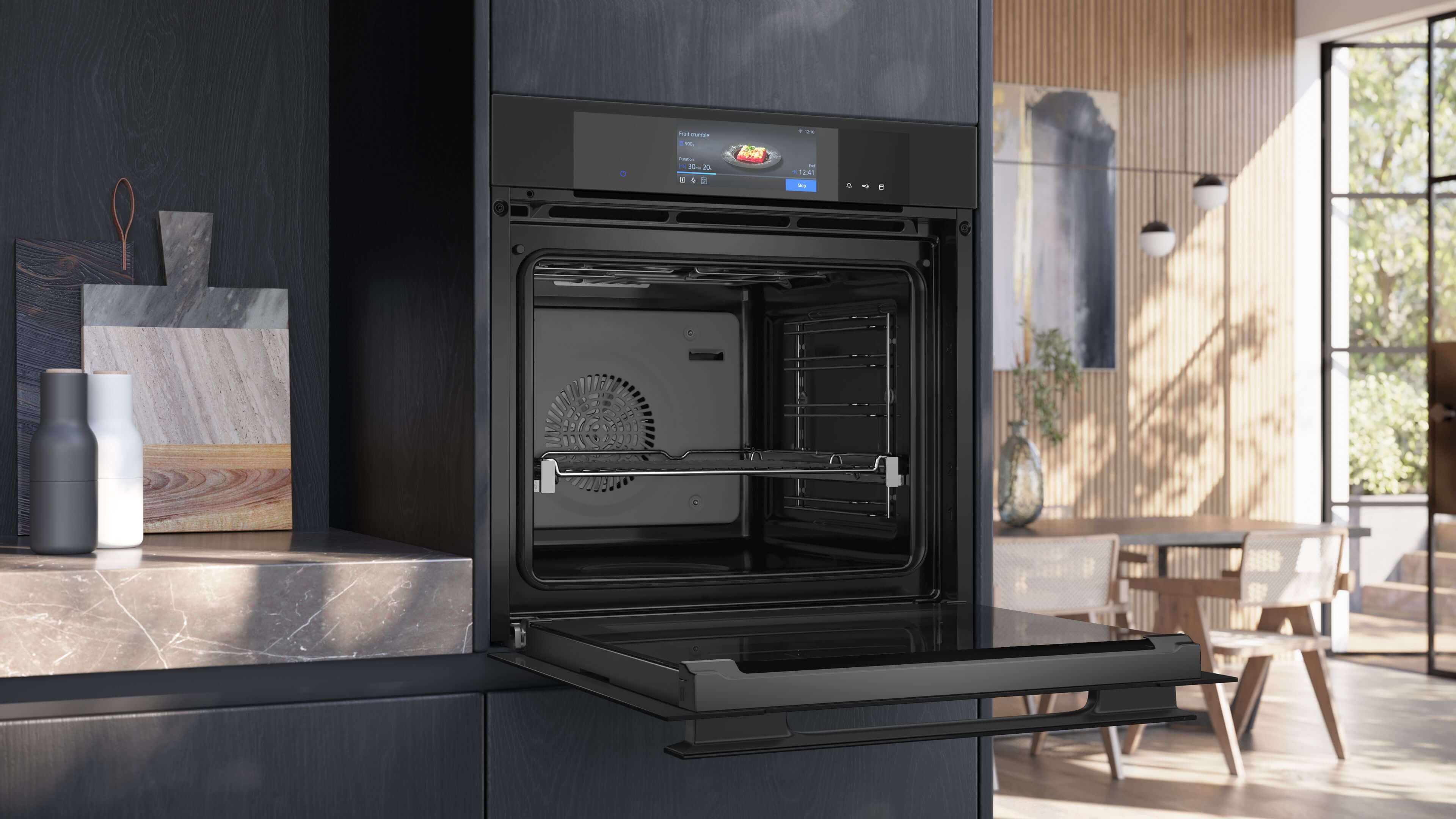 Geöffneter Siemens iQ700 Dampfbackofen in der Seitenansicht. Die Backofentür ist vollständig ausgeklappt und gibt den Blick auf den Garraum mit Teleskopauszug und das digitale Bedienmenü frei.