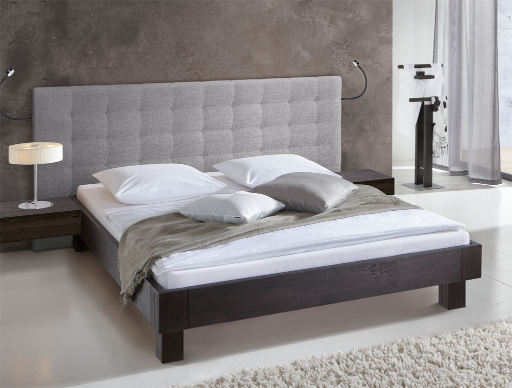 modernes Bett in schwarz mit grauem Polster als Wandpaneel stilvoll dekoriert in einem modernen Zimmer