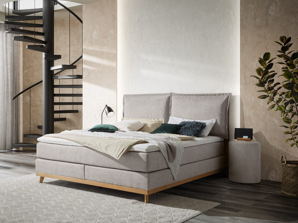 Boxspringbett Hasena Pronto Imelda in Hellgrau mit einem Holzfußgestell aus geölter Eiche in einem modern gestalteten Schlafzimmer.